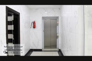 a bathroom with a walk in shower and a red fire extinguisher at المرجانة للشقق المفروشه للعائلات Al Murjana Furnished Apartments for Families in Al Baha