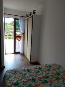 a bedroom with a bed and a door to a balcony at Casa Linda Ilhabela in Ilhabela