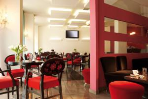 a restaurant with red chairs and tables and a tv at Anessis in Thessaloniki