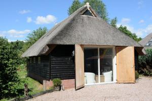 um pequeno edifício com telhado de palha e janela em De Violier em Eext