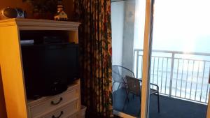 a television on a dresser with a balcony at JeffsCondos - 1 Bedroom - Camelot Resort in Myrtle Beach
