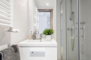 La salle de bains blanche est pourvue d'un lavabo et d'une douche. dans l'établissement Residencia Universitaria Claudio Coello, à Madrid