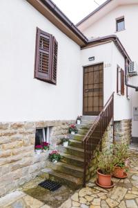 een wit huis met een trap en een raam bij Apartma Nika in Hrvatini