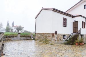 een wit huis met een stenen binnenplaats ervoor bij Apartma Nika in Hrvatini