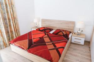 een slaapkamer met een bed met een rood en oranje dekbed bij Apartma Nika in Hrvatini