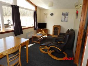 a living room with chairs and a table and a couch at Forest Glen Holiday Park in Invermoriston