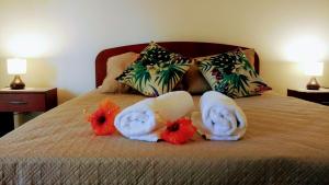 Una cama con toallas y animales de peluche. en Cabañas Te Maori, en Hanga Roa