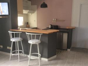 a kitchen with two bar stools at a counter at Jolie T2 au coeur du bourg in Carnac
