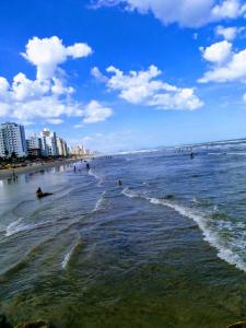 a group of people swimming in the ocean on a beach at Apartamento no Centro de Mongaguá in Mongaguá