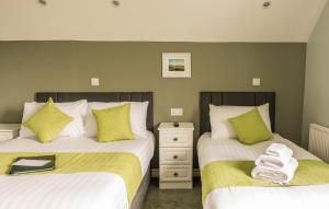 a bedroom with two beds with green and white sheets at The Pipers Rest in Doolin