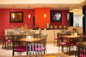 a restaurant with tables and chairs with red walls at Hotel Real Azteca Boulevard in León