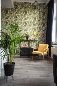 トルンにあるBoho Apartmentの植物を用いた壁紙と黄色い椅子が備わるリビングルーム