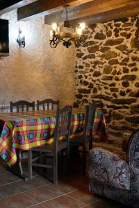 a dining room with a table and chairs and a stone wall at Casa Rural Xiromo in San Ciprián