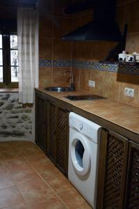 a kitchen with a washing machine and a sink at Casa Rural Xiromo in San Ciprián