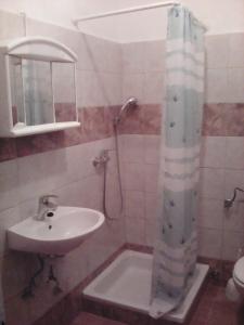 a bathroom with a sink and a shower with a shower curtain at Apartmani Ivona s pogledom na more in Podgora