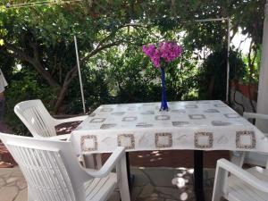 a white table with a vase of flowers on it at Apartmani Ivona s pogledom na more in Podgora