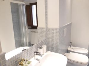 a bathroom with a sink and a toilet and a mirror at La Corte Antica in Pienza