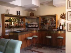 un bar con sgabelli in una stanza con alcolici di Hotel Ipanema a Taormina