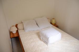 ルカートにあるMaisonnette La Franquiの小さなベッドルーム(白いベッド、スツール付)