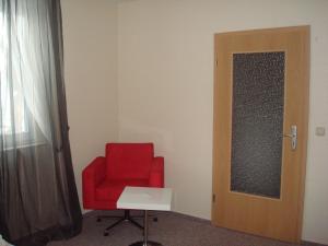 a red chair in a room with a door at Gästehaus Sol Tour in Ahrensfelde