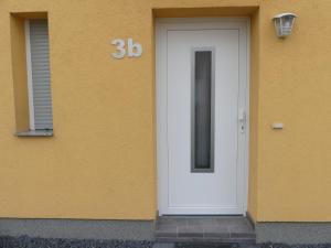 une porte blanche sur le côté du bâtiment dans l'établissement Ferienwohnung Anke - Apartment 3b, à Heinsberg