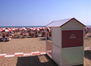 un edificio su una spiaggia con ombrelloni rossi e bianchi di Giovanna Rooms a Caorle