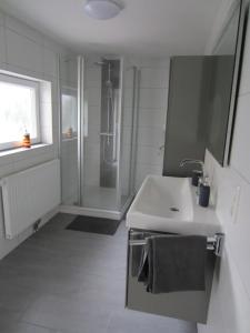 ein weißes Badezimmer mit Waschbecken und Dusche in der Unterkunft Ferienhaus Kluntje in Emden + 25 Fotos