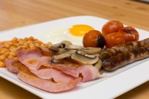 a plate of food with eggs bacon beans corn and tomatoes at The Bay Boutique Bed and Breakfast in Freshwater