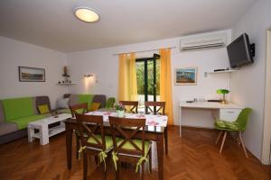 ein Wohnzimmer mit einem Tisch und grünen Stühlen in der Unterkunft Apartment with terrace and sea view in Mali Lošinj