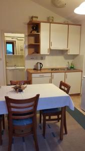 una cocina con mesa y sillas y una cocina con armarios blancos. en Apartments Villa Martinuzzi, en Rovinj