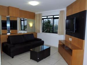 sala de estar con sofá y TV de pantalla plana en Flats em Ponta Negra, 1 e 2 qtos, en Natal