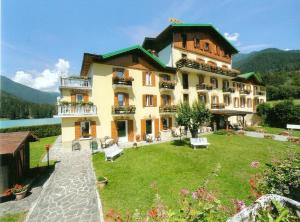 a large building with a lawn in front of it at Hotel Juventus in Auronzo di Cadore
