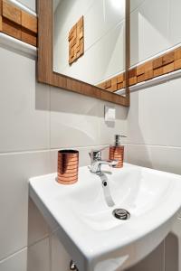 ein Badezimmer mit einem weißen Waschbecken und einem Spiegel in der Unterkunft JM Apartments zamieszkaj w Centrum in Krakau