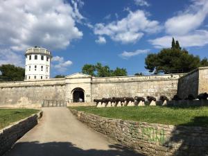 a building with a tower and a stone wall with a building at Apartment Volme in Pula