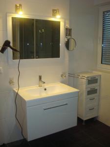 ein weißes Badezimmer mit einem Waschbecken und einem Spiegel in der Unterkunft Gästehaus Sol Tour in Ahrensfelde