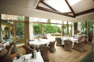 un restaurante con mesas y sillas blancas y ventanas en Wellness & Thermal Retreat Das Mühlbach en Bad Füssing