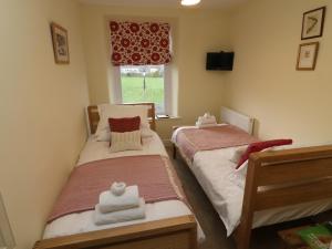two twin beds in a room with a window at Inglenook Guest House in Ingleton