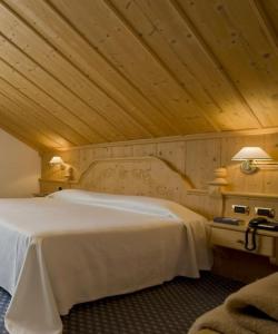 een slaapkamer met een wit bed en een houten plafond bij Chalet Al Lago in San Vito di Cadore