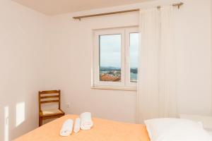 a bedroom with a bed with a chair and a window at Apartments Sky in Šibenik