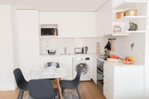 una cucina bianca con lavatrice, tavolo e sedie di Vale Quiet & Comfort Flat a Lisbona