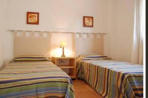 Dos camas en una habitación con una lámpara sobre una mesa. en Apartamento en Nerja, en Nerja