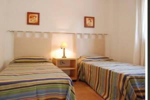 two beds in a room with a lamp on a table at Apartamento en Nerja in Nerja