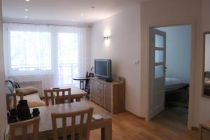 a living room with a television and a table and chairs at Pati Ferien Apartmens in Łukęcin