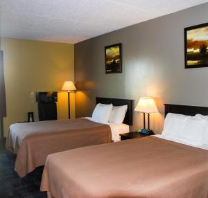 Habitación de hotel con 2 camas y 2 lámparas en Sunlac Inn Lakota en Lakota