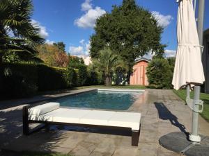 un banco blanco junto a una piscina con sombrilla en Petite Maison Andernos, en Andernos-les-Bains