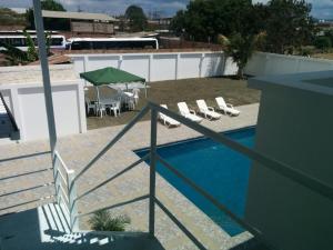 a swimming pool with lounge chairs and a green umbrella at Manta Airport Hotel in Manta