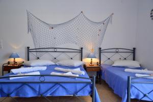 two beds in a bedroom with blue sheets and pillows at Aperanto galazio in Agia Kiriaki Beach