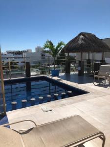 a swimming pool with a straw umbrella on a building at Condo Mar Arena in Playa del Carmen
