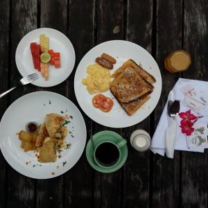 three plates of breakfast food on a wooden table at Kebun Villas & Resort in Senggigi