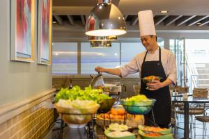 a chef standing in a kitchen preparing food at Evergreen Place Siam by UHG in Bangkok